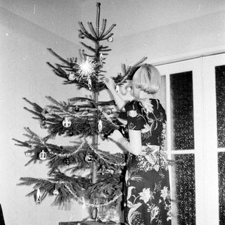 Woman decorates a Christmas tree in a vintage room.