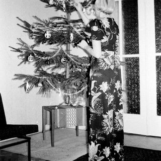 Woman decorates a Christmas tree in a vintage room.
