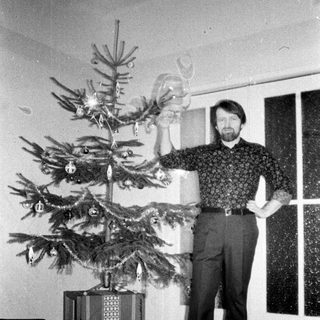 Man stands near a decorated Christmas tree indoors.