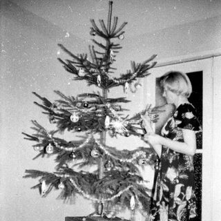 Woman decorating a small Christmas tree indoors.