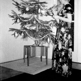 Woman decorating a small Christmas tree indoors.