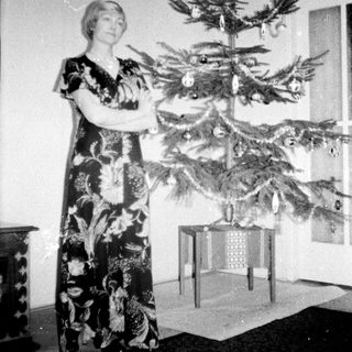 Woman stands near a small, decorated Christmas tree.