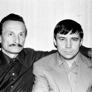 Here's a brief summary of the image: Two men standing close together, posing for a portrait.
