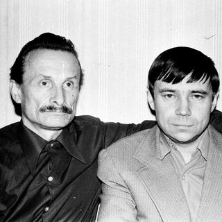 Here's a brief summary of the image: Two men standing close together, posing for a portrait.