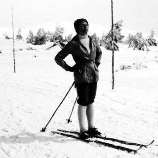 Man stands on skis in a snowy, wooded landscape.