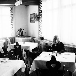Black and white photo of a woman in a dining room.