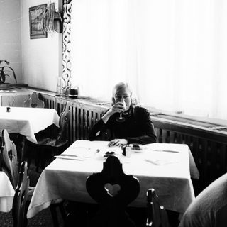 Black and white photo of a woman in a dining room.