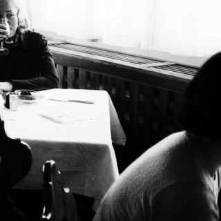 Black and white photo of a woman in a dining room.
