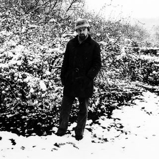 Man stands in a snowy, wooded landscape.