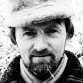 Man in a hat stands in a snowy, wintry landscape.