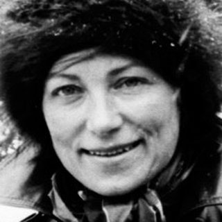 Woman in fur hat stands in a snowy, wintry landscape.