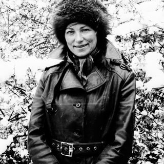 Woman in fur hat stands in a snowy, wintry landscape.