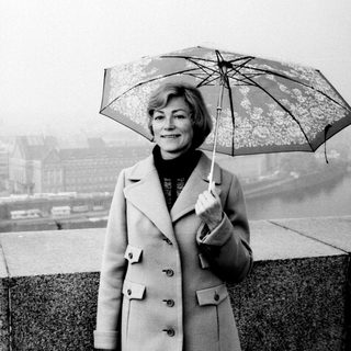 Woman with umbrella stands overlooking a foggy cityscape.