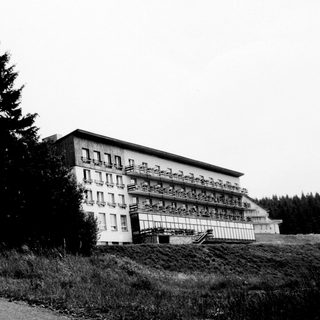 A building sits on a hill, trees in the background.