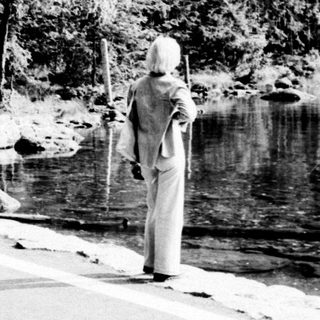 Monk walks along a snowy lakeside road.
