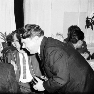 Men in suits converse during a meeting or event.