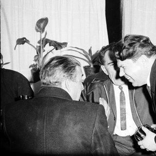 Men in suits converse during a meeting or event.