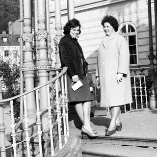 Two women in coats stand on a stone staircase.