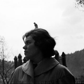 Woman in vintage clothing stands looking off to the side.