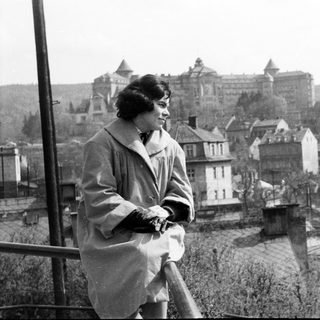 Woman stands overlooking a town with a large building.