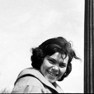 Woman smiles next to a tall, fluted column.