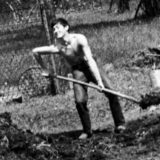 Man using a tool in a garden landscape.