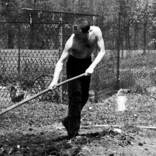 Man using a tool in a garden area.