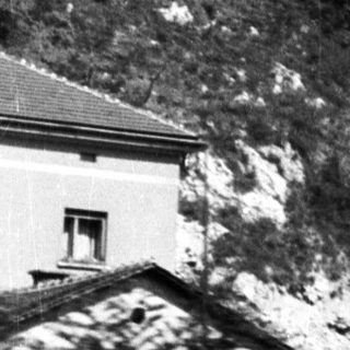 Here's a brief summary of the image: Lush, forested hillside with a building on the peak.
