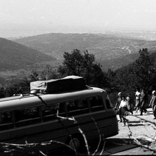 Group of people exit bus on a hillside road.