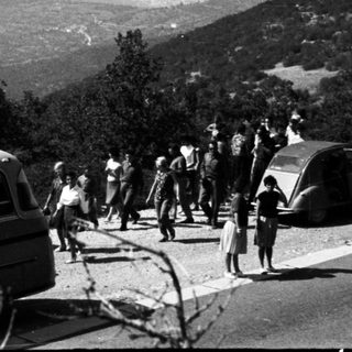 Group of people exit bus on a hillside road.