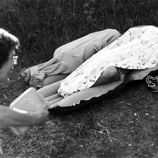 Here's a brief summary of the image: Two people relax on an inflatable mattress outdoors.