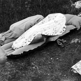 Here's a brief summary of the image: Two people relax on an inflatable mattress outdoors.