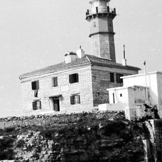 Lighthouse sits atop a rocky coast overlooking the sea.
