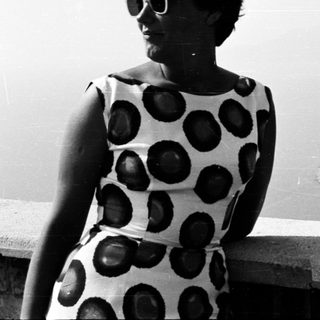 Woman in a patterned dress overlooking a coastal landscape.