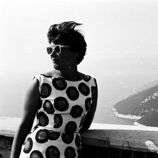 Woman in a patterned dress overlooking a coastal landscape.