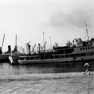 Black and white photo of ships docked at a harbor.