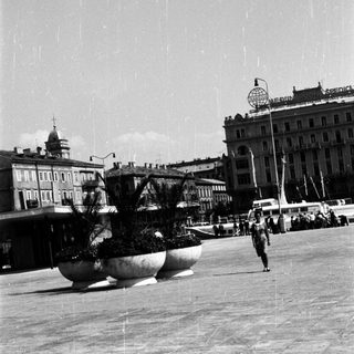 Black and white image of a public square with buildings.