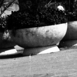 Black and white image of a public square with buildings.