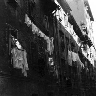 Narrow street with laundry hanging between tall buildings.