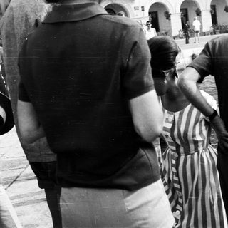 Here's a brief summary of the image: Man in striped dress being escorted, seemingly restrained.