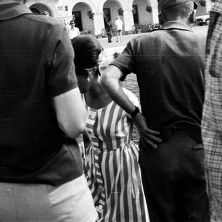Here's a brief summary of the image: Man in striped dress being escorted, seemingly restrained.