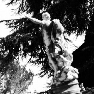 Woman sits near a statue in a park.