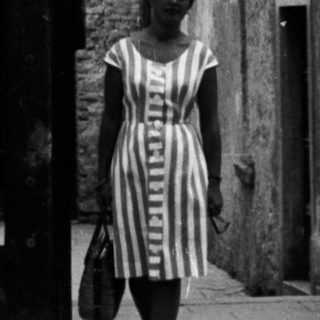 Woman walks through a monumental, arched doorway.