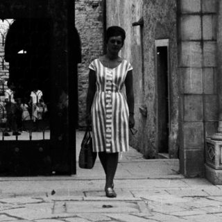 Woman walks through a monumental, arched doorway.
