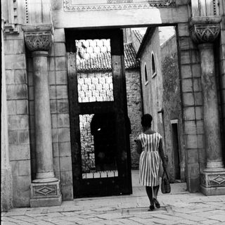 Woman walks through an arched doorway with mosaic.