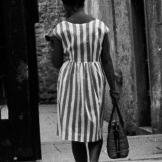 Woman walks through an arched doorway with mosaic.