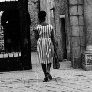 Woman walks through an arched doorway with mosaic.