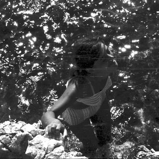 Person submerged underwater, surrounded by light and rocks.