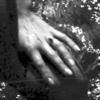 Person in swimwear emerging from water, sunlight sparkling.