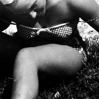 Woman sits by water, holding a turtle.